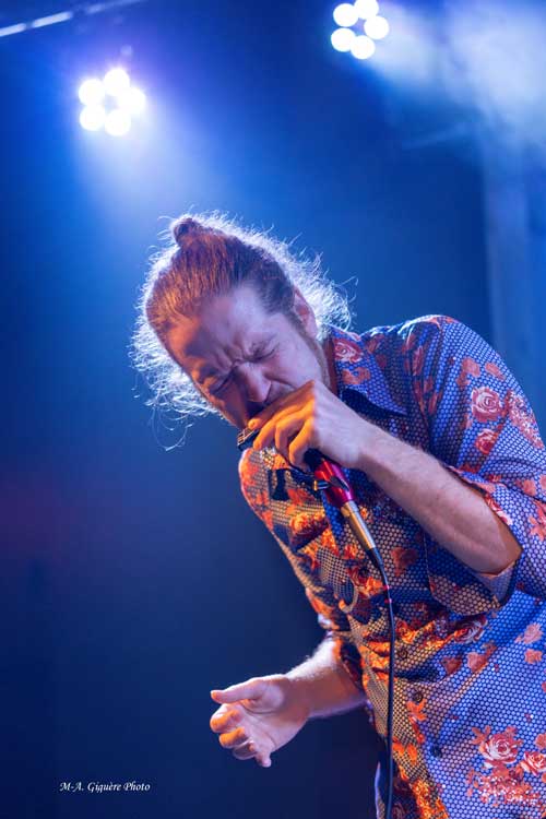 Benjamin Vaudeville en spectacle, jouant de l'harmonica sur scène
